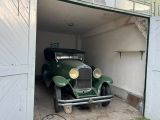 a green car in a garage with a door open