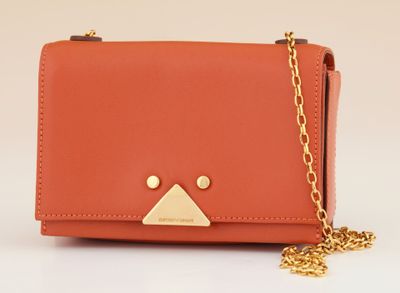 an orange purse with a gold triangle on the front and a chain around it