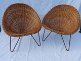 pair of wicker chairs with metal legs on a white background
