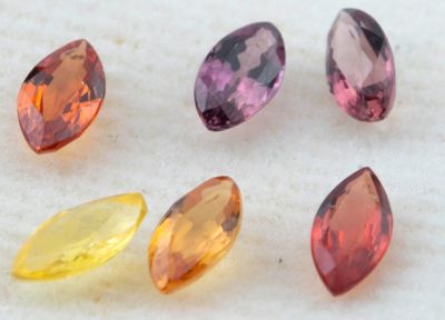 cinq pierres précieuses de couleurs différentes sont disposées en ligne sur une surface blanche