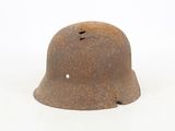 a rusty helmet with holes on it on a white surface