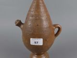 an old brown vase with a tag on it sitting on a table