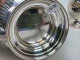 a silver cup sitting on a table next to a silver cup