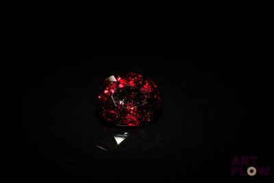 a close up of a red glass ball on a black surface