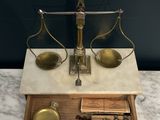 an antique scale on a marble counter top with a wooden drawer
