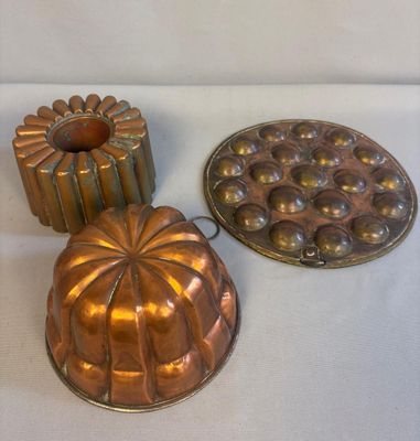 deux casseroles en métal et un moule à gâteau posés sur un plan de travail blanc