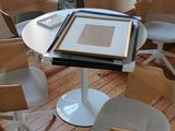 plusieurs chaises et une table dans une pièce où se trouve un tableau posé sur la table