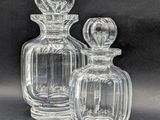 deux bouteilles en verre transparent posées l'une à côté de l'autre sur une surface noire
