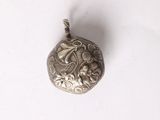 a silver pendant with a flower design on it