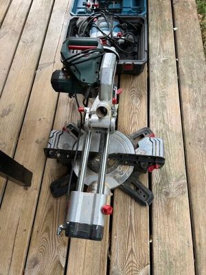 une scie circulaire posée sur une terrasse en bois, à côté d'une boîte à outils