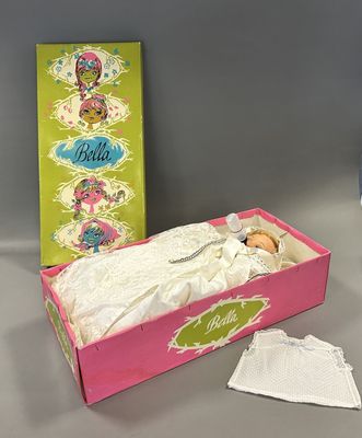 une boîte rose contenant une poupée, à côté d'une boîte de mouchoirs