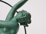 a green statue of a woman holding a flower in her hand