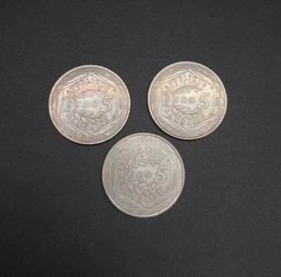 three silver coins sitting on top of a black surface
