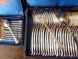 a lot of silver spoons and forks in a blue box