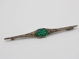 a close up of a green and white broocher on a white surface