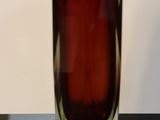 a red glass vase sitting on a black table