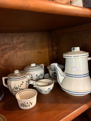 une étagère en bois sur laquelle sont posées une théière et des tasses