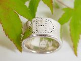 a close up of a silver ring with a leaf in the background