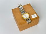 une boîte en bois sur laquelle est posée une montre argentée et jaune