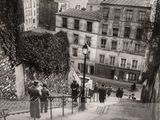 a black and white photo of a group of people walking up a steep hill