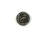an old coin with a bird on it sitting on top of a white surface