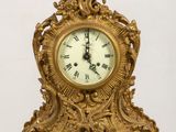 a gold clock sitting on top of a wooden table