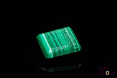 a close up of a green stone on a black surface