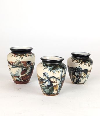 three vases are sitting on a white surface, one has a painting on it