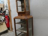a tall wooden cabinet with a glass door on top of it