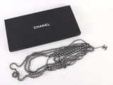 Collier Chanel dans un coffret noir, avec une chaîne sur fond blanc