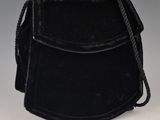un vieux sac à main noir auquel est accrochée une chaîne sur le côté