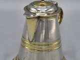 an antique silver and gold coffee pot sitting on a white surface