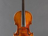 an old violin sitting on a stand against a gray background