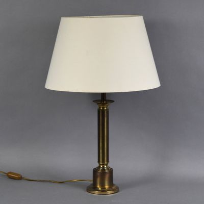 a brass table lamp with a white shade on a grey background