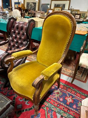 une chaise jaune au milieu d'une pièce remplie de meubles anciens