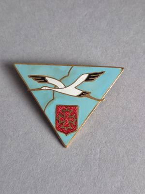 un gros plan d'un oiseau sur fond bleu, avec un emblème rouge et blanc