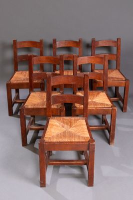 six chaises en bois sont alignées en rangée sur une surface grise