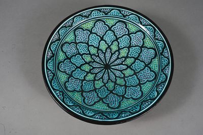 a blue and green plate with a flower design on it