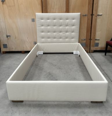 un lit avec une tête et un pied de lit blancs dans une chambre