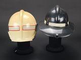 two fire fighters helmets on a black surface with a gray background