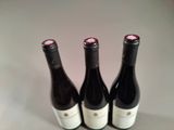 three bottles of wine sit on a table next to each other