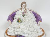 figurine représentant une femme en robe blanche, assise sur une chaise violette