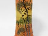 an orange vase with a painting of a tree and a bird on it