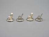 four pieces of silver metal are sitting on a white surface