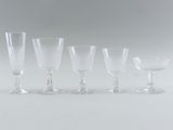 four clear wine glasses sitting next to each other on a white surface