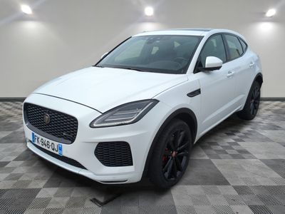 un SUV Jaguar blanc garé sur un sol à damier dans un garage