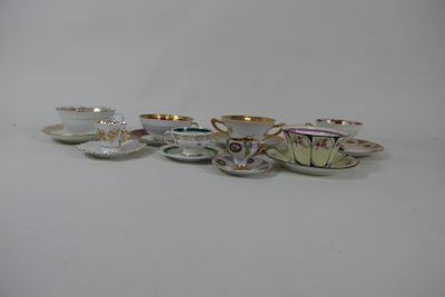 several cups and saucers are lined up on a white surface