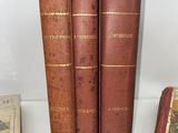 three old books sitting on top of a white shelf next to each other