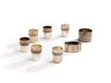 six silver cups are arranged in a circle on a white surface