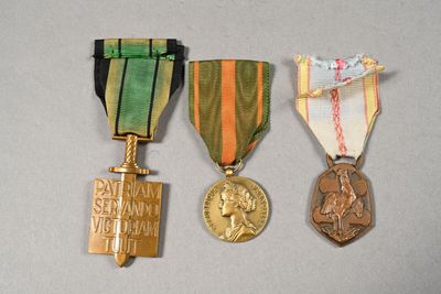 three medals are displayed on a white surface with a gray background